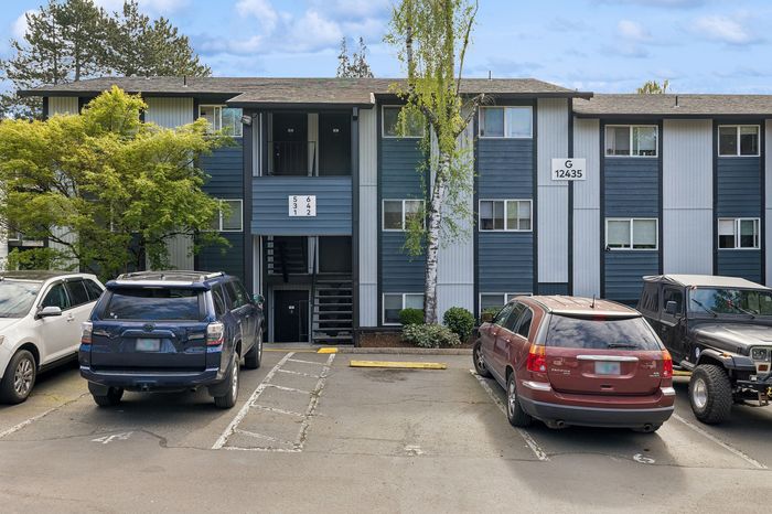 Charming apartment building with lush greenery and spacious parking, offering a serene living environment.