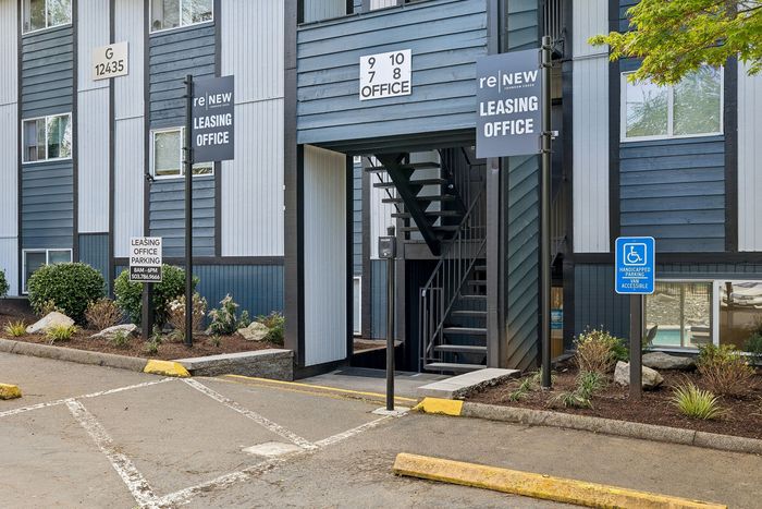 Modern leasing office entrance with accessibility parking at ReNew Johnson Creek, surrounded by well-maintained landscaping.