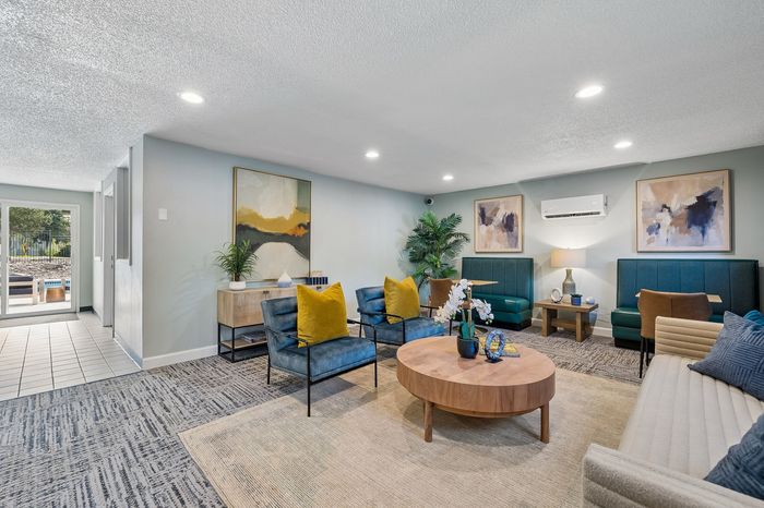 Stylish and modern lounge area with blue accent chairs, vibrant artwork, and natural lighting, ideal for relaxation and social gatherings.