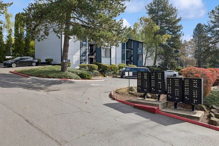 Charming apartment complex surrounded by lush greenery and convenient parking, offering a serene and welcoming atmosphere.