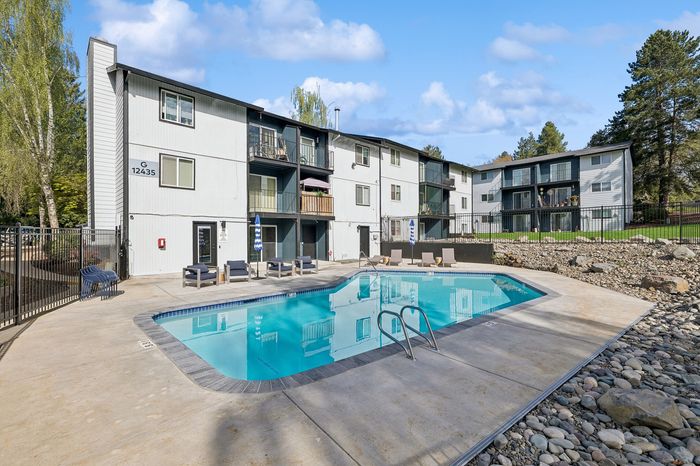 Charming apartment complex with a refreshing swimming pool and inviting outdoor seating, perfect for relaxation and leisure.
