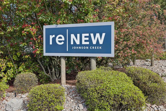 Inviting sign for Renew Johnson Creek nestled among lush greenery.