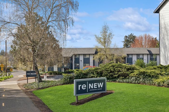 Beautifully landscaped apartment complex with lush greenery and modern architecture at ReNew Johnson Creek.