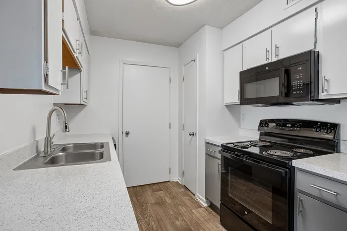 Contemporary kitchen with sleek black appliances, modern white cabinetry, and elegant countertops.