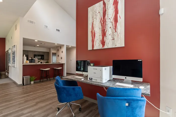 Chic apartment interior featuring a modern office nook with dual computer setup and stylish bar seating area by the kitchen.