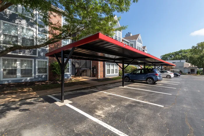 Charming apartment complex with modern carport parking, surrounded by lush greenery and elegant architecture.