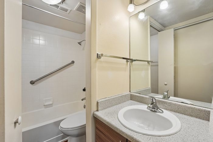 Bright and cozy bathroom with elegant granite countertop, gleaming fixtures, and a pristine bathtub with a modern shower.