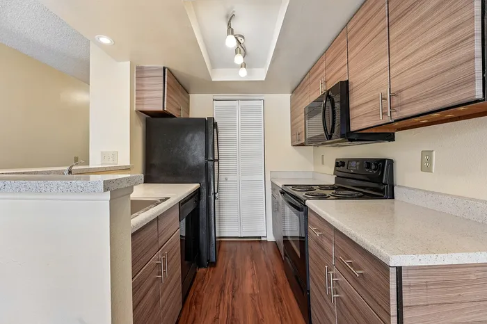 Modern kitchen with sleek wooden cabinets, elegant countertops, and stainless steel appliances, perfect for culinary creativity.