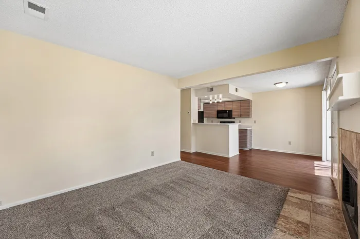 Inviting living space with plush carpeting, open kitchen with modern cabinetry, and warm natural light.