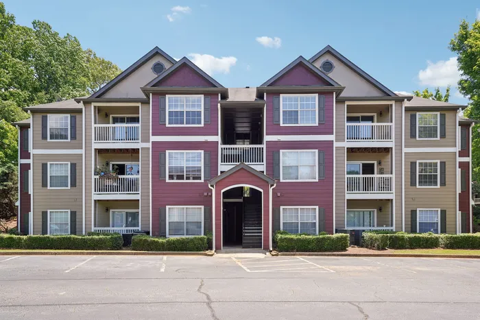Charming three-story apartment building featuring elegant balconies and surrounded by lush greenery.