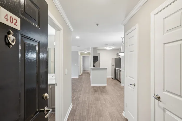 Inviting apartment entrance with elegant wood flooring, leading to a bright and modern kitchen and hallway.