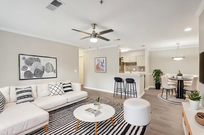 Modern open-plan living area featuring a stylish lounge with chic decor, a compact yet elegant dining nook, and a contemporary kitchen with a cozy breakfast bar.