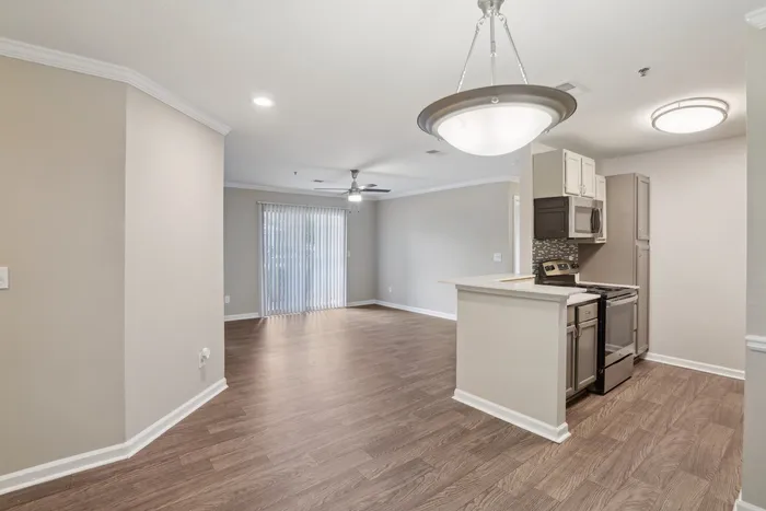 Modern, open-plan living and kitchen area with stylish wood flooring and elegant lighting, perfect for a cozy and inviting atmosphere.