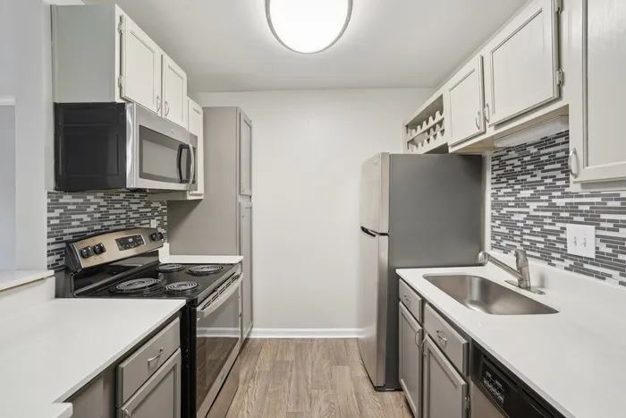 Modern kitchen with sleek stainless steel appliances, mosaic tile backsplash, and elegant cabinetry.