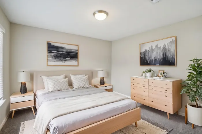 Bright and elegant bedroom with modern decor, featuring a cozy bed, chic wooden furniture, and serene artwork, creating a relaxing atmosphere.
