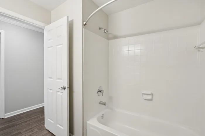 Sleek and modern bathroom featuring pristine white tiles, a curved shower rod for added space, and elegant fixtures.