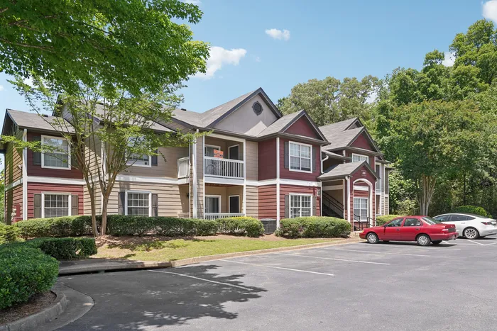 Charming multi-unit apartment complex with classic architecture, set amidst lush greenery and ample parking space.
