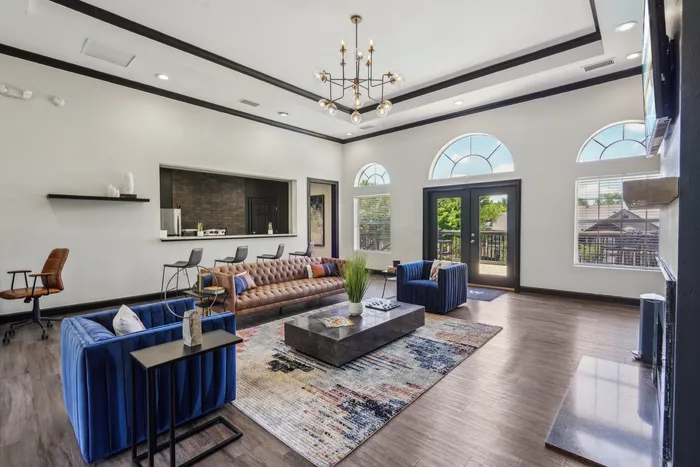 Elegant open-concept living space with chic modern furniture, stylish chandelier, and expansive windows providing natural light.