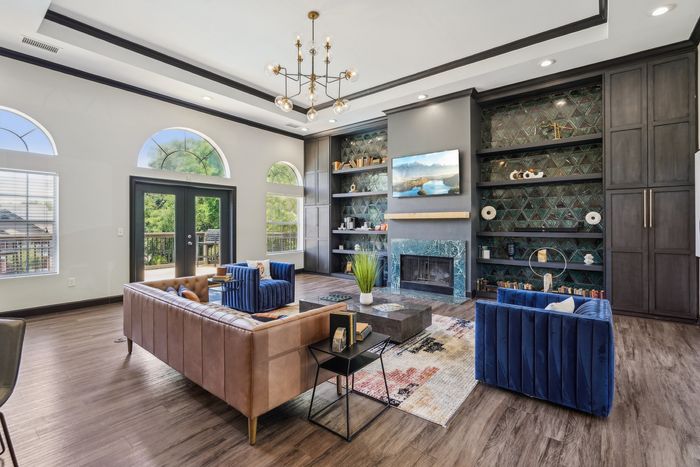 Elegant living room with stylish decor, featuring rich wood floors, a chic chandelier, and a cozy fireplace surrounded by modern shelving.