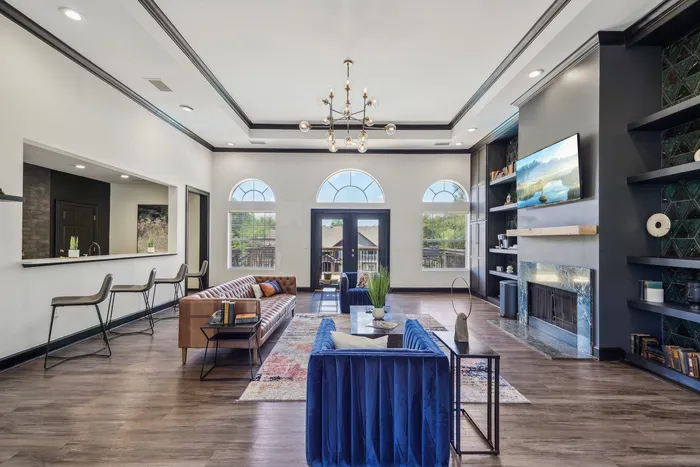 Elegant living room featuring chic decor, a modern chandelier, stylish bar seating, and large arched windows for abundant natural light.