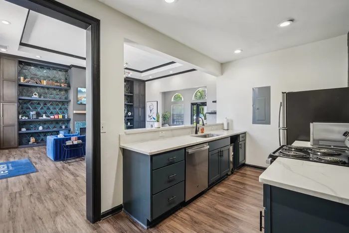 Elegant open-plan kitchen with modern appliances, sleek countertops, and a view into a stylish living room with built-in shelves and contemporary decor.