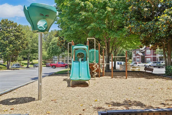 Charming outdoor playground with slide and climbing structures surrounded by lush greenery, ideal for family fun.