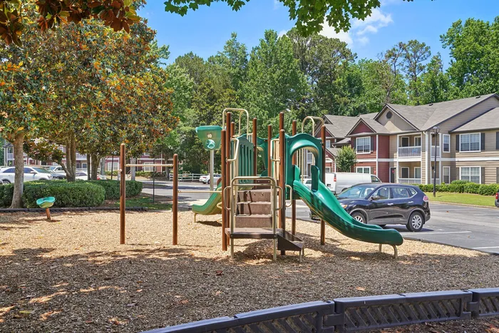 Charming apartment community with scenic playground and lush greenery, perfect for family living.