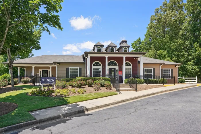 Charming apartment complex exterior with classic architecture, inviting entry, and lush landscaping under a bright blue sky.