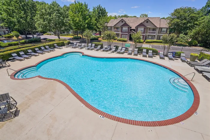 Inviting outdoor swimming pool with sleek design surrounded by stylish lounge chairs and lush greenery, perfect for relaxation and summer enjoyment.