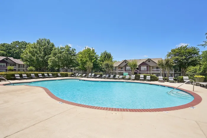 Inviting outdoor swimming pool with comfortable lounge chairs and lush greenery, perfect for relaxation in a serene residential setting.