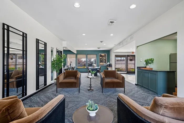 Inviting apartment lobby with modern decor, featuring plush brown armchairs, stylish mirrors, and vibrant greenery.