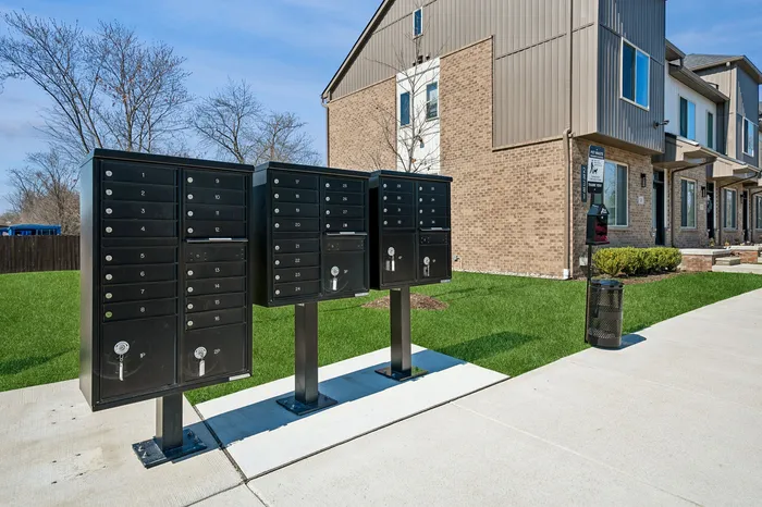 Modern apartment complex with secure black mailboxes and lush green landscaping, offering a welcoming and stylish community living environment.