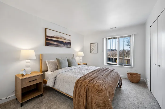 Bright and cozy bedroom featuring a plush bed with elegant bedding, modern decor, and a picturesque window view.