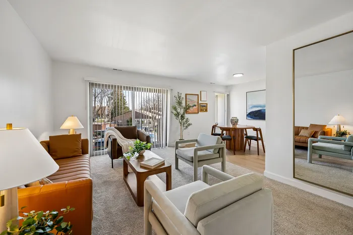 Bright and inviting living room with modern furniture and a large window offering abundant natural light.