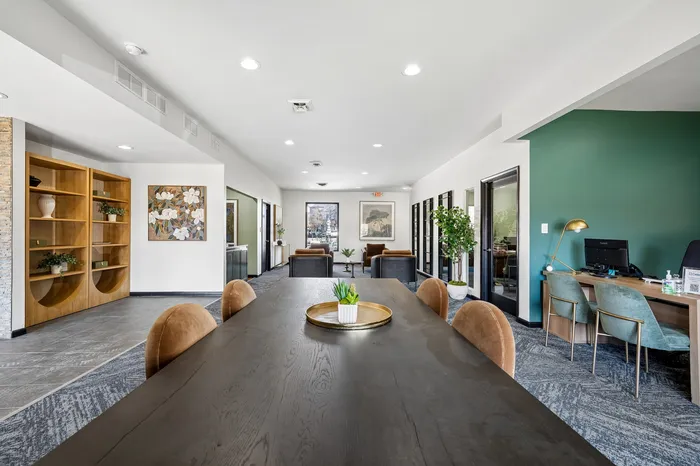 Modern, open-concept living space featuring a chic conference table, plush seating, and vibrant greenery accents.