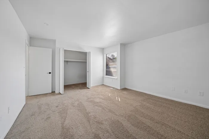Bright and spacious bedroom with plush carpet, large closet, and ample natural light.