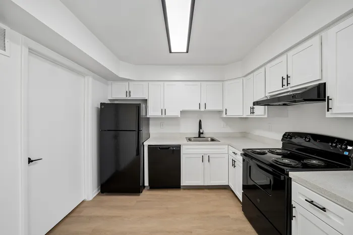 Modern kitchen featuring sleek black appliances, white cabinetry, and elegant countertops, offering a stylish and functional cooking space.