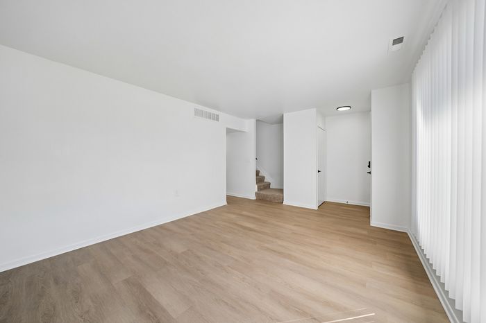 Bright, modern living space with elegant wood flooring and sleek white walls, perfect for stylish interior design.