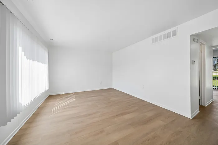 Bright, airy room with elegant wood flooring and large windows, perfect for creating your dream living space.