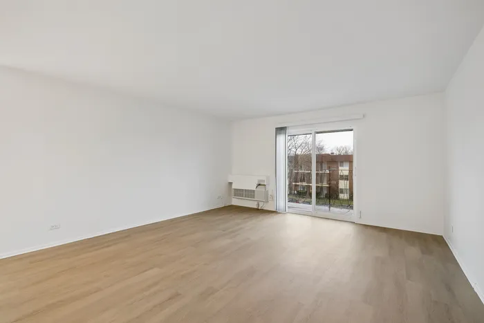 Bright living room with sleek hardwood floors and expansive windows offering a serene view of nature.