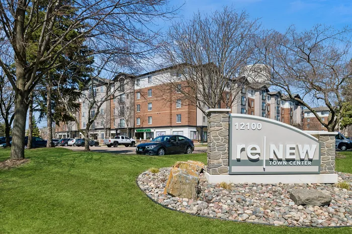 Modern apartment complex exterior with lush green landscaping at ReNew Town Center, featuring ample parking and stylish architecture.