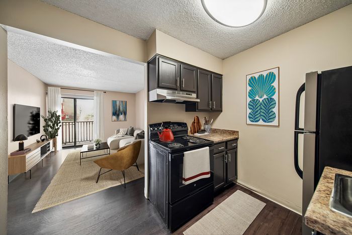 Contemporary open-concept apartment with a cozy living area featuring stylish furniture, large windows, and a modern kitchen with sleek cabinetry and appliances.