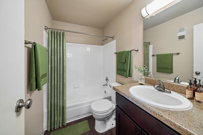 Chic bathroom design with modern dark wood vanity, cream countertop, and elegant green accents, featuring a bright spacious layout.