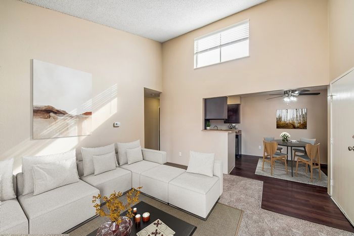 Bright living room with cozy sectional sofa, open-concept dining area, and modern kitchen, featuring high ceilings and elegant decor.