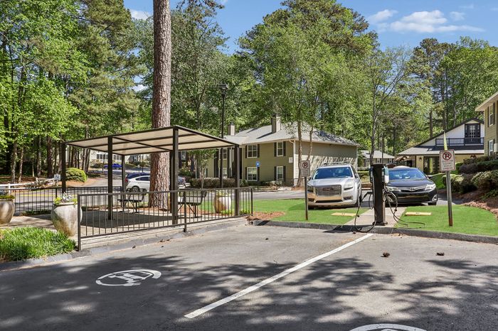 Serene apartment community with electric vehicle charging station, surrounded by lush greenery and modern amenities.