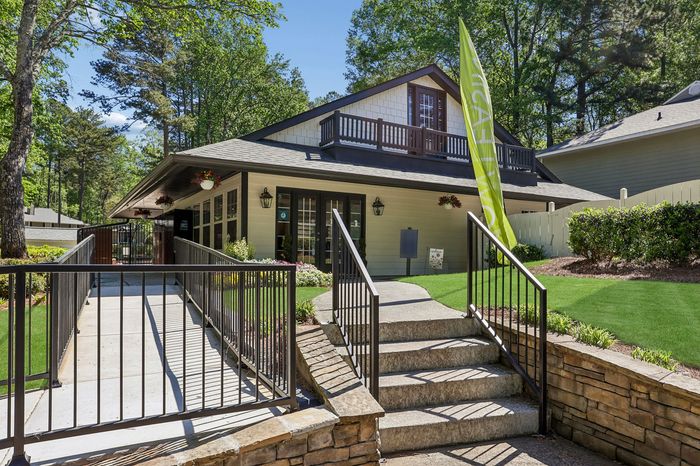 Charming clubhouse entrance with lush landscaping, inviting pathways, and a welcoming atmosphere.