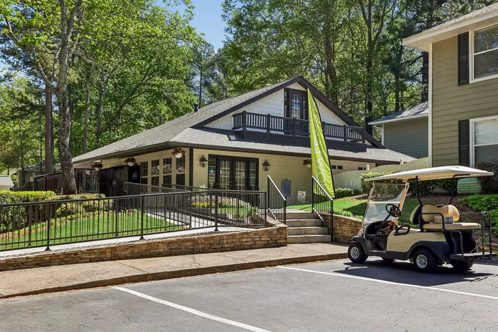 Charming apartment community with a stylish clubhouse, surrounded by lush greenery, and a convenient golf cart for easy transport.