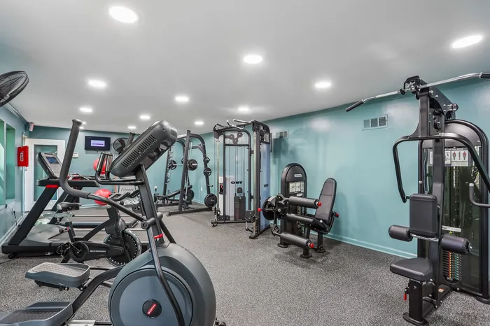 Modern apartment gym with state-of-the-art exercise equipment and vibrant blue walls, perfect for fitness enthusiasts.