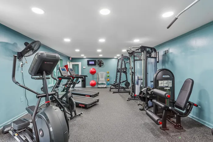 Modern fitness room with state-of-the-art exercise equipment, spacious layout, and sleek lighting.