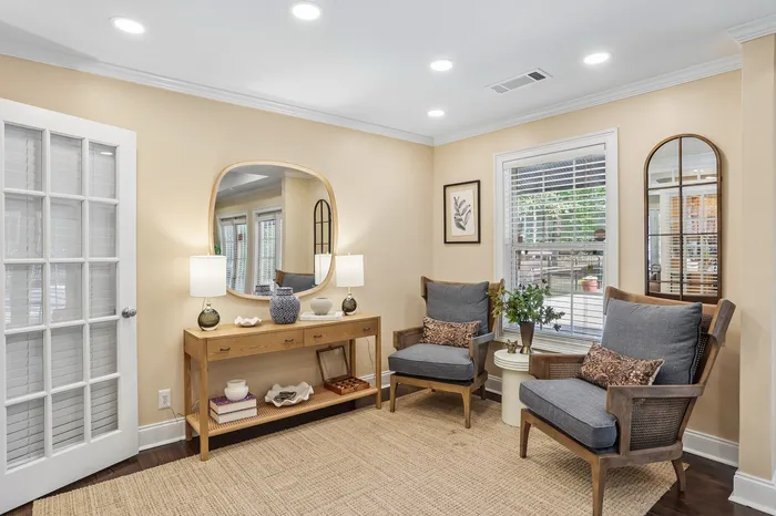 Elegant home interior with cozy seating area, featuring stylish chairs, a wooden console table, modern decor, and large windows for natural light.